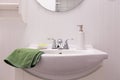 Detail of all white bathroom with sink, porcelain soap dispenser and green bar of soap in dish Royalty Free Stock Photo