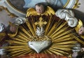 Detail of the altar in the church of Mittenwalde with a silver heart, a cross, stylized sunrays and the heads of angels with wings