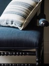 Detail of an antique armchair with dark blue linen fabric upholstery and cushion with striped pattern, home decor and