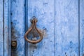 Detail of an antique door knocker on a blue wooden door with a lock Royalty Free Stock Photo