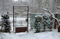 Detail of an Art Nouveau gate with an oval decorative element of a rusty metal garden gate connected to a fence. The yew hedge is