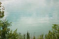 Detail of the azure surface of a flooded quarry between deciduous branches.