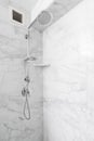 A shower with marble tiles and chrome faucet.