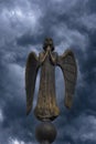 Detail of beautiful bronze statue of an angel with wings against the dark sky with clouds. Beautiful angel with a stormy sky Royalty Free Stock Photo