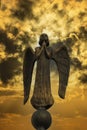 Detail of beautiful bronze statue of an angel with wings against the dark sky with clouds. Beautiful angel with a stormy sky Royalty Free Stock Photo