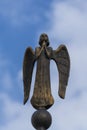 Detail of beautiful bronze statue of an angel with wings against the sky. Beautiful angel with a blue sky background with space