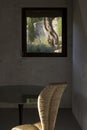 Detail of a beautiful wicker chair, a modern glass table, and a view of the green garden with olive tree Royalty Free Stock Photo