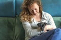 Detail of a beautiful woman with curly brown hair. Sitting on a sofa, smiling with a Jack Russel Terrier puppy in her arms Royalty Free Stock Photo