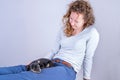 Detail of a beautiful woman with glasses and curly brown hair, Sitting smiling with a Jack Russel Terrier puppy on her legs