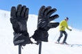 Detail on black ski gloves on ski poles with blurred skier in ba