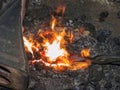 Forge with strong flames. Pliers hold horse shoe