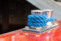 Detail of blue rope coiled around a steel bollard at a yacht Royalty Free Stock Photo