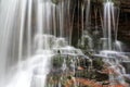 Detail of blurred water falling over moss and red rock