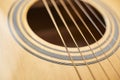 Detail of the body of a light wood guitar, the soundhole and strings Royalty Free Stock Photo