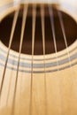 Detail of the body of a light wood guitar, the soundhole and strings Royalty Free Stock Photo