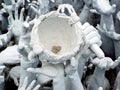 Detail of the bowl with coins held by hands in the lake of hands next to the White Temple in Chiang Rai, Thailand