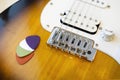 Detail of the bridge of an electric guitar with four colored picks, the pickups and strings out of focus in the background
