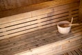 Detail of bucket and wood spoon on a wooden bench. Small interior sauna