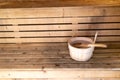 Detail of bucket and wood spoon on a wooden bench. Small interior sauna