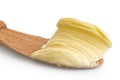 Detail of butter spread on wooden knife on white background.