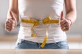 Detail of a butter-tied measuring tape around woman& x27;s waist with her fingers up Royalty Free Stock Photo