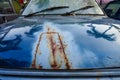 Detail of the car's front hood's cracked and rusted paint. Unbranded automobile that is rusted and broken