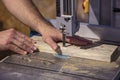 Detail of a carpenter`s hand next to a band saw blade