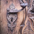 Detail of a carved wooden portal with wrought iron handle. Royalty Free Stock Photo