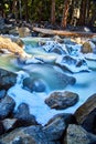 Detail of cascading waters over frosty and snowy rocks in early spring