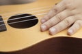 Detail of child's hand playing with ukulele Royalty Free Stock Photo