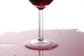 Detail close up on a red wineglass with red wine spilled on the table on white background with copy space for your text