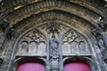 Detail closeup of exterior gothic medieval church stone entrance with round arch, small voussoirs, holy figure holding sword, red Royalty Free Stock Photo