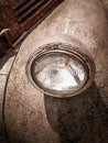 Detail and closeup of old round light of old car covered with rust with cracked painting