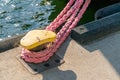 Detail closeup shot of yellow steel harbour knob with a strong pink rope attached to it, securing a moored boat. Royalty Free Stock Photo