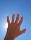 Detail color photography of womans hand catching sun rays and blue sky Royalty Free Stock Photo