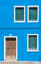 Detail with a colorful house windows and door entrance with blue painted wall and wooden shutters in Burano, Italy Royalty Free Stock Photo