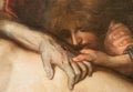 Detail of colorful religious painting showing a sad Maria Magdalene kissing a wound on the hand of Jesus Christ