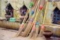 Detail of colorful rustic brooms against weathered wall
