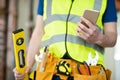 Detail Of Construction Worker On Building Site Wearing Tool Belt Using Mobile Phone Royalty Free Stock Photo