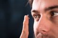 Detail of a contact lens on a man's finger which is putting on lens to his eye.