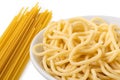 Detail of cooked spaghetti in a white ceramic bowl next to uncooked spaghetti on white Royalty Free Stock Photo