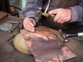 Detail of a craftsman engraves a copper plate with a hammer and chisel