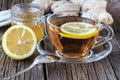 detail of cup of ginger tea with lemon and fresh ginger on wooden cutting board Royalty Free Stock Photo