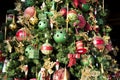 Hangings on Christmas tree like green balls, red ribbons and toys, Details of richly decorated Christmas tree