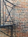 Detail of Decorative Wrought Iron Urban Fire Escape Against a Red and Black Brick Wall