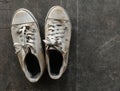 Dirty and old white shoes on dirty cement ground