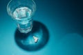 Detail of drug flank powder with unfocused face in the reflection of the mirrorzenithal photography of glass of water and pills