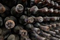 Detail of a dusty old wine bottle aging in a rack surrounded by other old wines