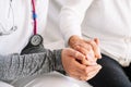 Detail of an elderly woman's hands being caressed by the hands of a young nurse