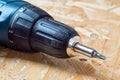 Detail of electric screwdriver with torx bit lying on chip board. Blurred background